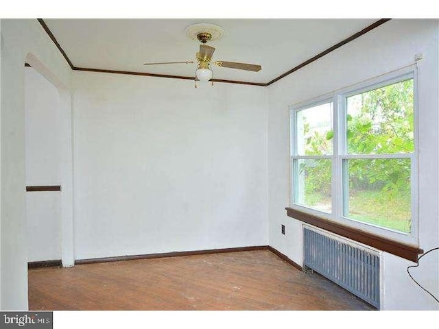 empty room with dark wood-type flooring, radiator heating unit, and ceiling fan