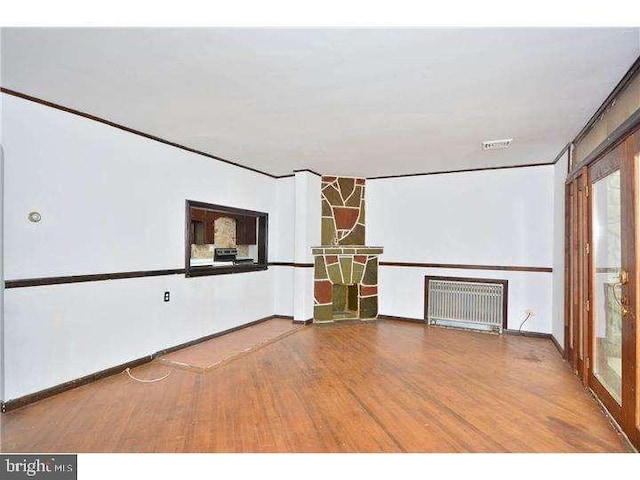 empty room with hardwood / wood-style flooring, ornamental molding, and radiator