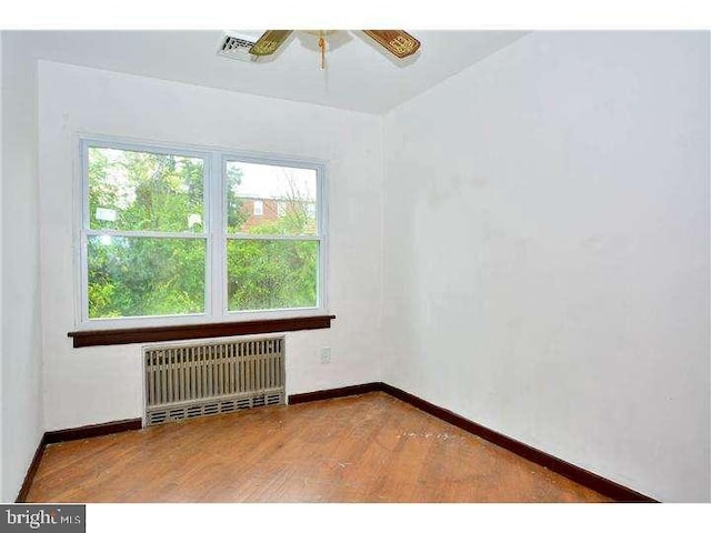 spare room featuring hardwood / wood-style flooring and radiator heating unit