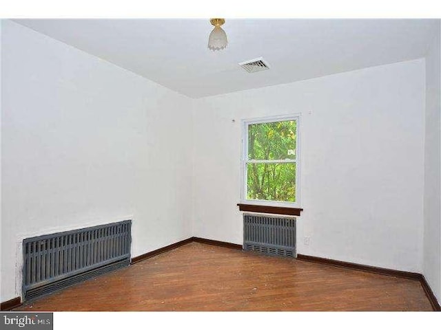 empty room with radiator and dark hardwood / wood-style floors