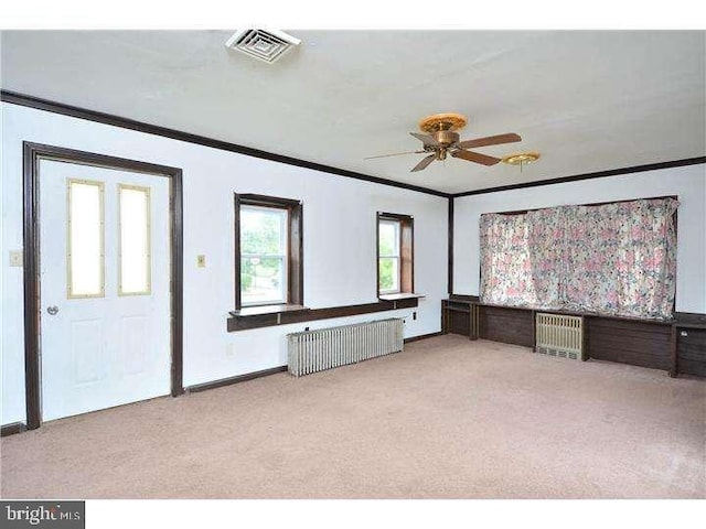 interior space featuring radiator, light colored carpet, ornamental molding, and ceiling fan