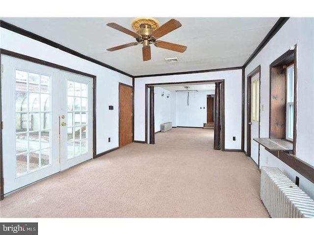 empty room featuring light carpet, ornamental molding, french doors, and ceiling fan