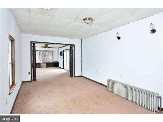 empty room featuring radiator heating unit and light carpet