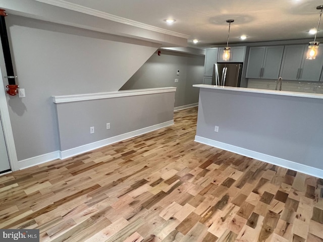 interior space featuring light hardwood / wood-style flooring, hanging light fixtures, gray cabinets, and stainless steel refrigerator