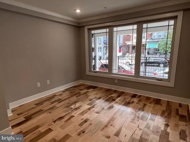 empty room with plenty of natural light, ornamental molding, and light wood-type flooring