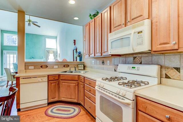 kitchen with sink, white appliances, ceiling fan, backsplash, and light wood-type flooring