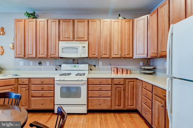 kitchen with sink, white appliances, and light wood-type flooring