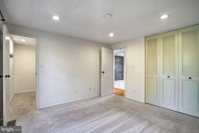 unfurnished bedroom with light carpet, a textured ceiling, and a closet