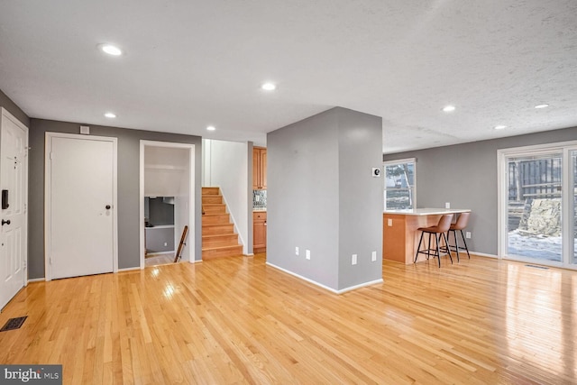 unfurnished living room featuring light hardwood / wood-style flooring and a textured ceiling