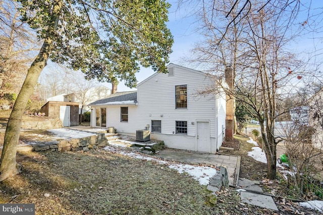 rear view of house with central AC and a storage shed