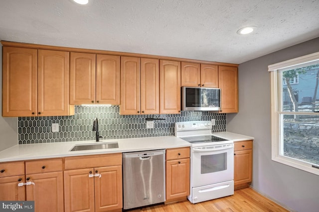 kitchen featuring tasteful backsplash, sink, light hardwood / wood-style floors, stainless steel appliances, and a textured ceiling