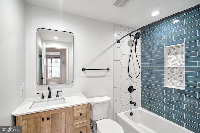 full bathroom featuring vanity, tiled shower / bath combo, toilet, and a textured ceiling