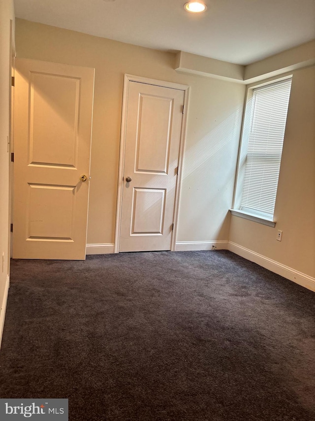 unfurnished room with dark colored carpet