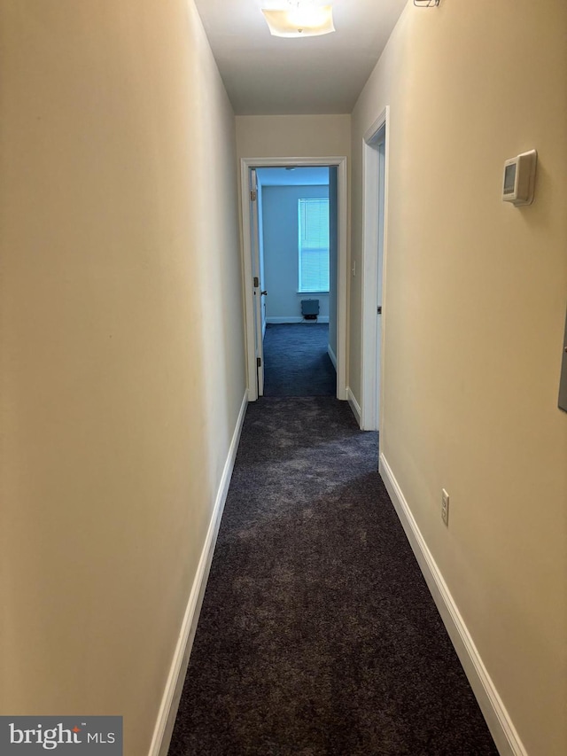 hallway featuring dark colored carpet