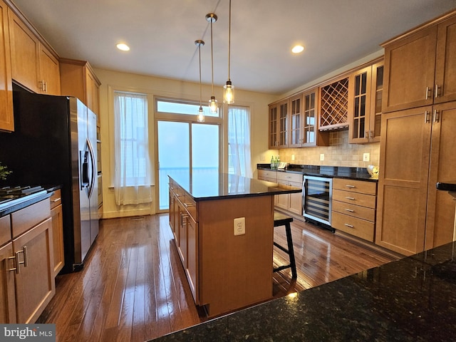 kitchen with a kitchen island, dark hardwood / wood-style floors, pendant lighting, beverage cooler, and backsplash