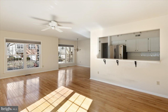 interior space with ceiling fan with notable chandelier and light wood-type flooring