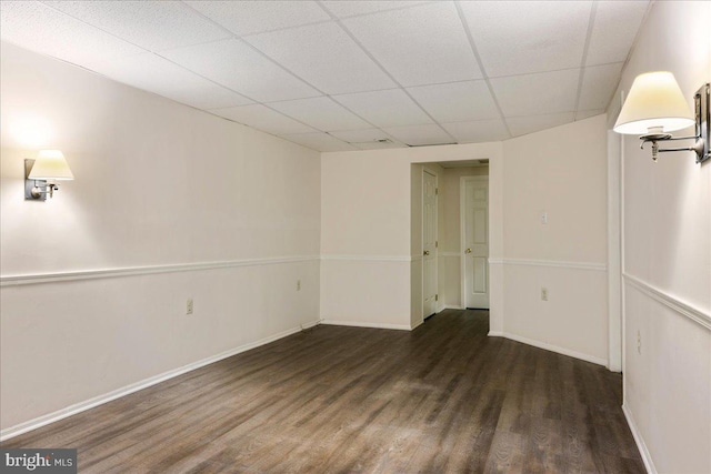 spare room with dark wood-type flooring and a drop ceiling