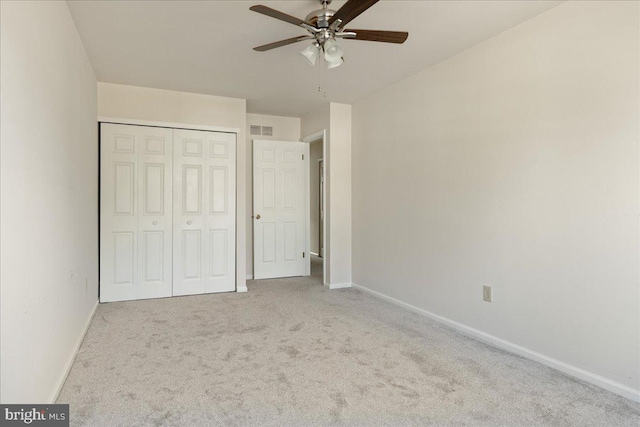 unfurnished bedroom featuring light colored carpet, ceiling fan, and a closet