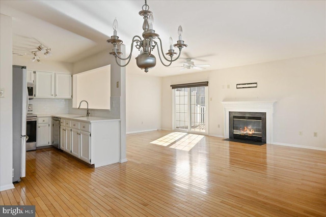 kitchen with stainless steel appliances, sink, light hardwood / wood-style flooring, and white cabinets