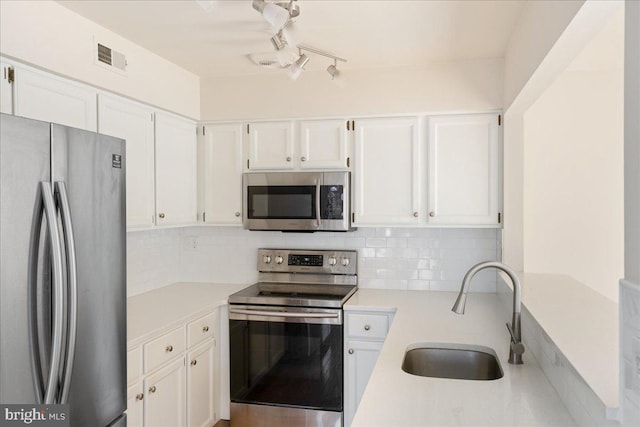 kitchen with white cabinetry, stainless steel appliances, sink, and backsplash