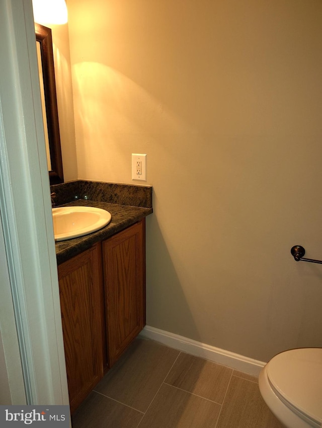 half bathroom featuring vanity, toilet, and baseboards