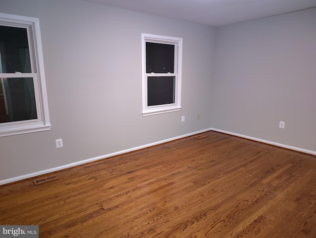 empty room featuring visible vents, baseboards, and wood finished floors