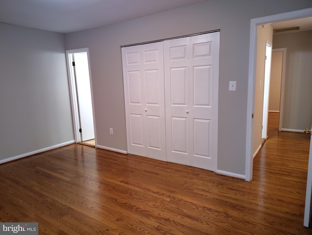 unfurnished bedroom with a closet, baseboards, and wood finished floors