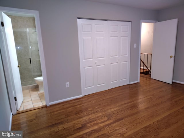 unfurnished bedroom featuring wood finished floors, a closet, and baseboards