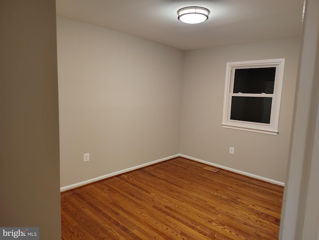 spare room with built in shelves, visible vents, baseboards, and wood finished floors