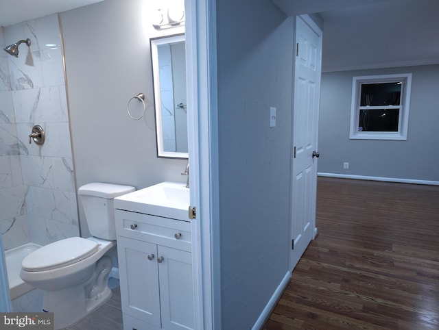 full bathroom with tiled shower, toilet, wood finished floors, and vanity