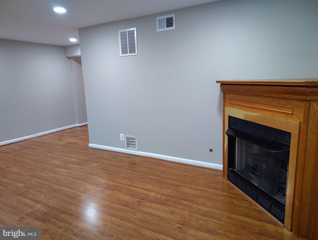 unfurnished living room with wood finished floors, a fireplace, and visible vents