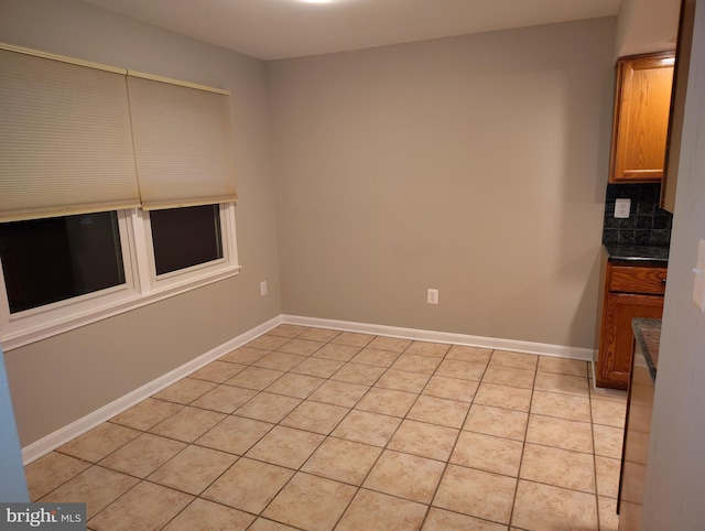 unfurnished dining area featuring light tile patterned flooring and baseboards