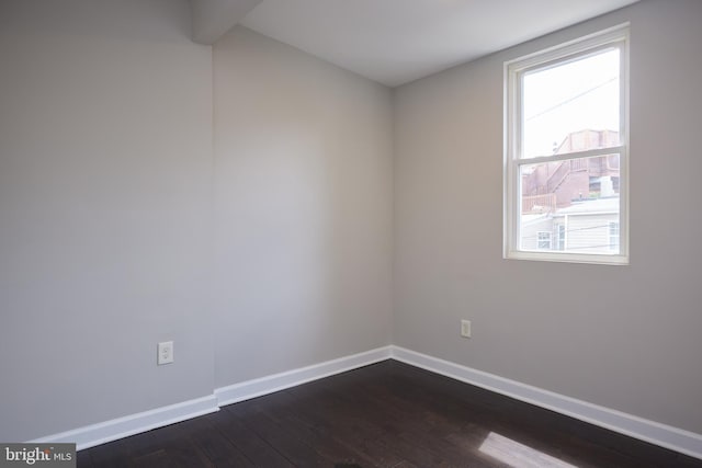 unfurnished room featuring baseboards and dark wood-type flooring