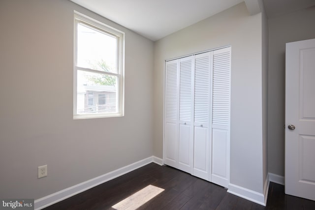 unfurnished bedroom featuring dark wood-style floors, baseboards, and a closet