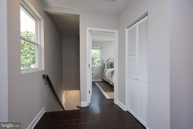 corridor featuring an upstairs landing, dark wood-style floors, and baseboards