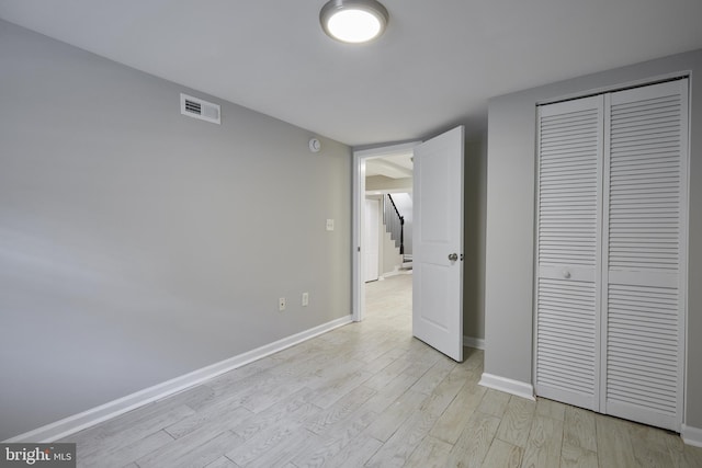 unfurnished bedroom featuring light wood-style floors, a closet, and baseboards