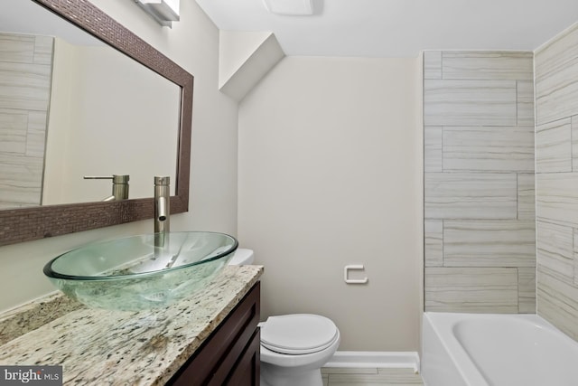 bathroom with toilet, vanity, and baseboards