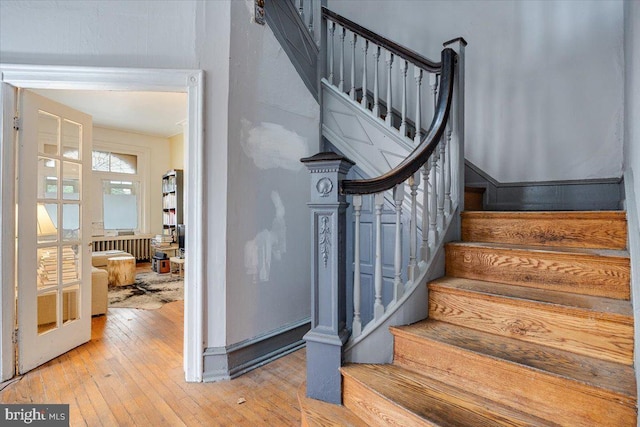 staircase with hardwood / wood-style flooring and radiator heating unit