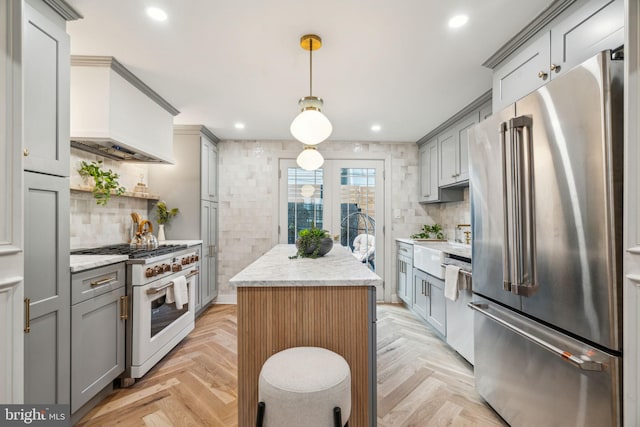 kitchen with gray cabinets, hanging light fixtures, premium appliances, light stone countertops, and a kitchen island