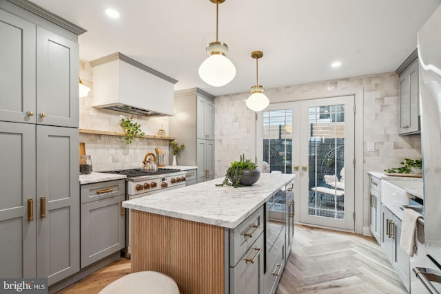 kitchen with gray cabinetry, decorative light fixtures, a center island, custom range hood, and light parquet floors