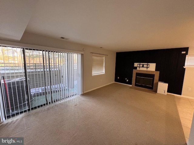 unfurnished living room with a tiled fireplace and carpet