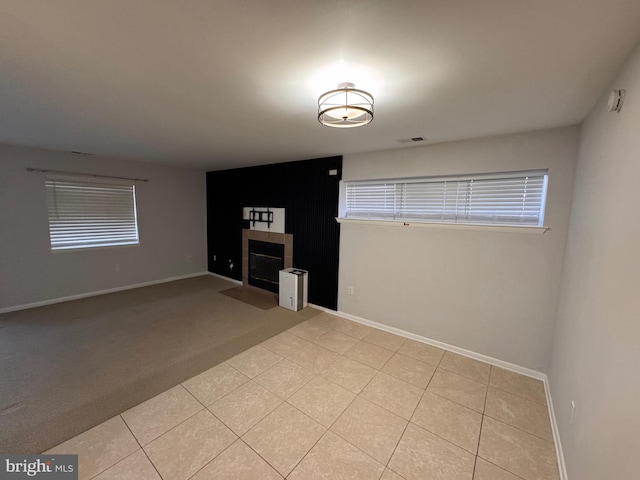 unfurnished living room featuring a tiled fireplace and light tile patterned floors