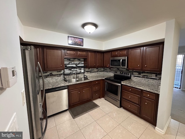 kitchen with sink, backsplash, light tile patterned floors, stainless steel appliances, and light stone countertops