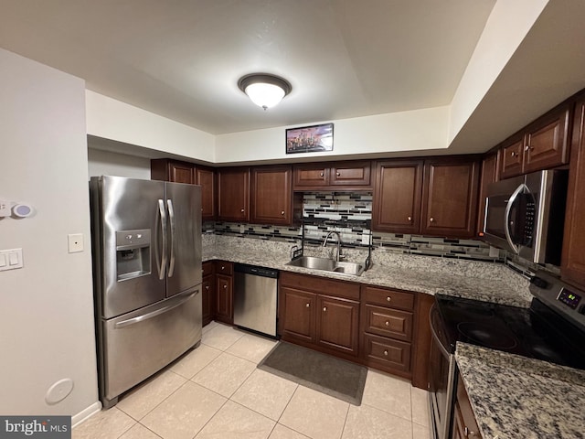 kitchen featuring light tile patterned flooring, sink, dark brown cabinets, appliances with stainless steel finishes, and light stone countertops