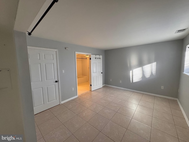 unfurnished bedroom featuring light tile patterned floors and ensuite bathroom