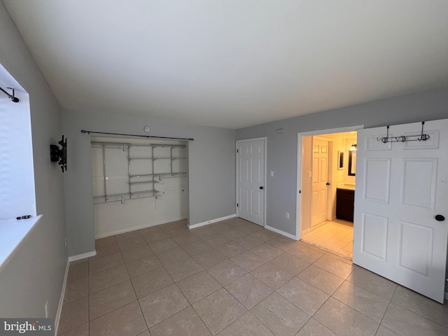 unfurnished bedroom with light tile patterned flooring, connected bathroom, and a closet