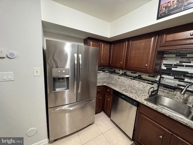 kitchen featuring sink, backsplash, light tile patterned floors, light stone counters, and stainless steel appliances