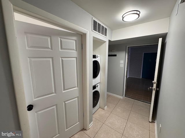 laundry room featuring light tile patterned flooring and stacked washer / dryer