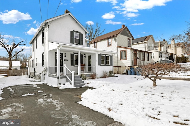 snow covered rear of property with covered porch