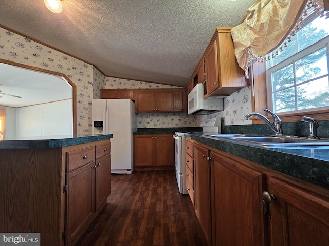 kitchen with vaulted ceiling, white appliances, a sink, and wallpapered walls